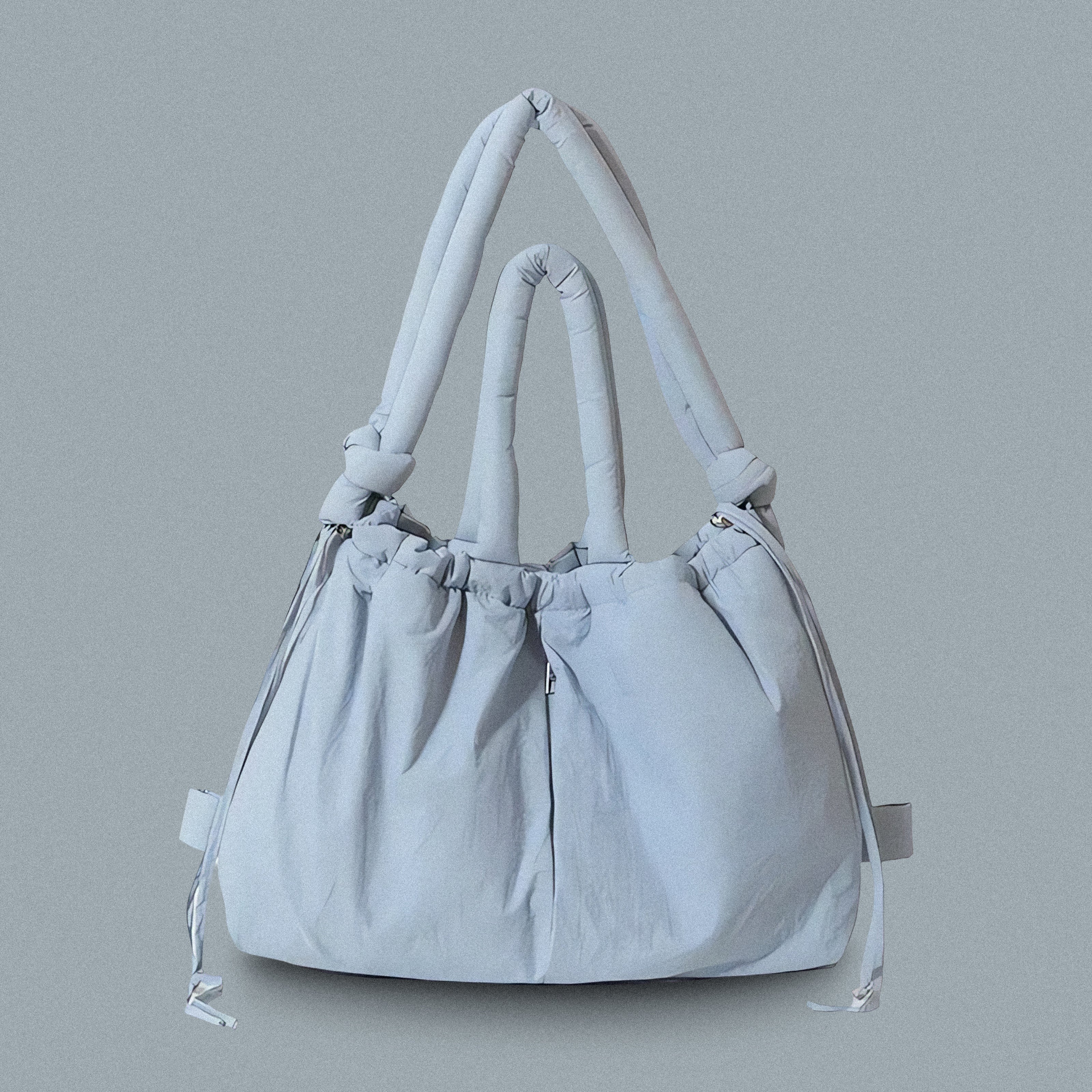 PLSH baby blue women’s designer puffer handbag on a blue background