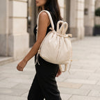 Woman walking outdoors with a PLSH designer white handbag backpack