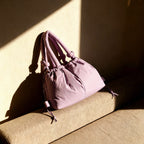 PLSH pink women's designer handbag on a beige surface with a soft shadow