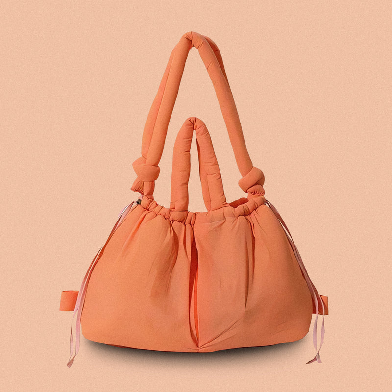 PLSH orange women’s designer puffer handbag on a orange background