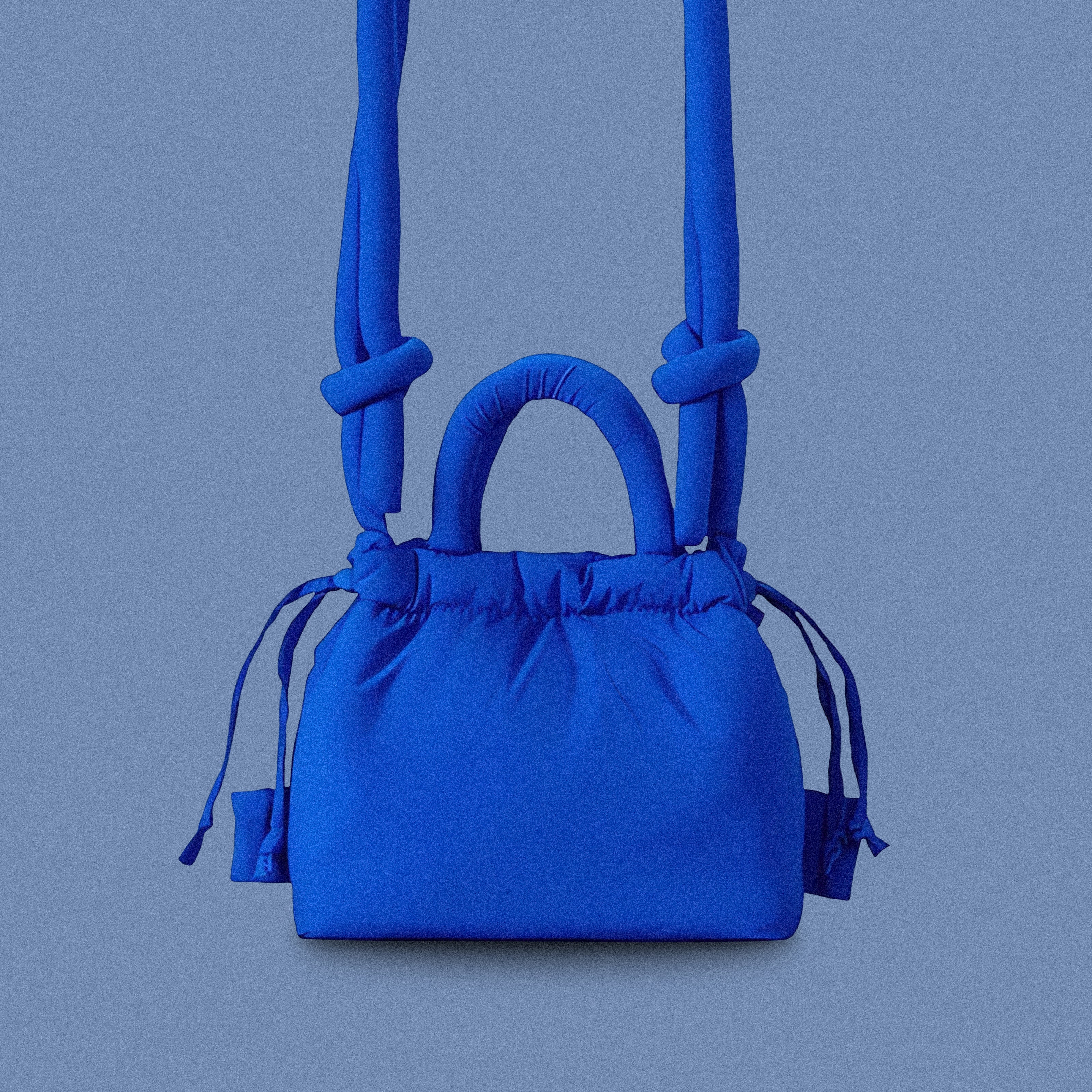 PLSH blue women’s designer puffer handbag on a blue background