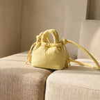 PLSH yellow women's designer handbag with drawstring on a beige sofa