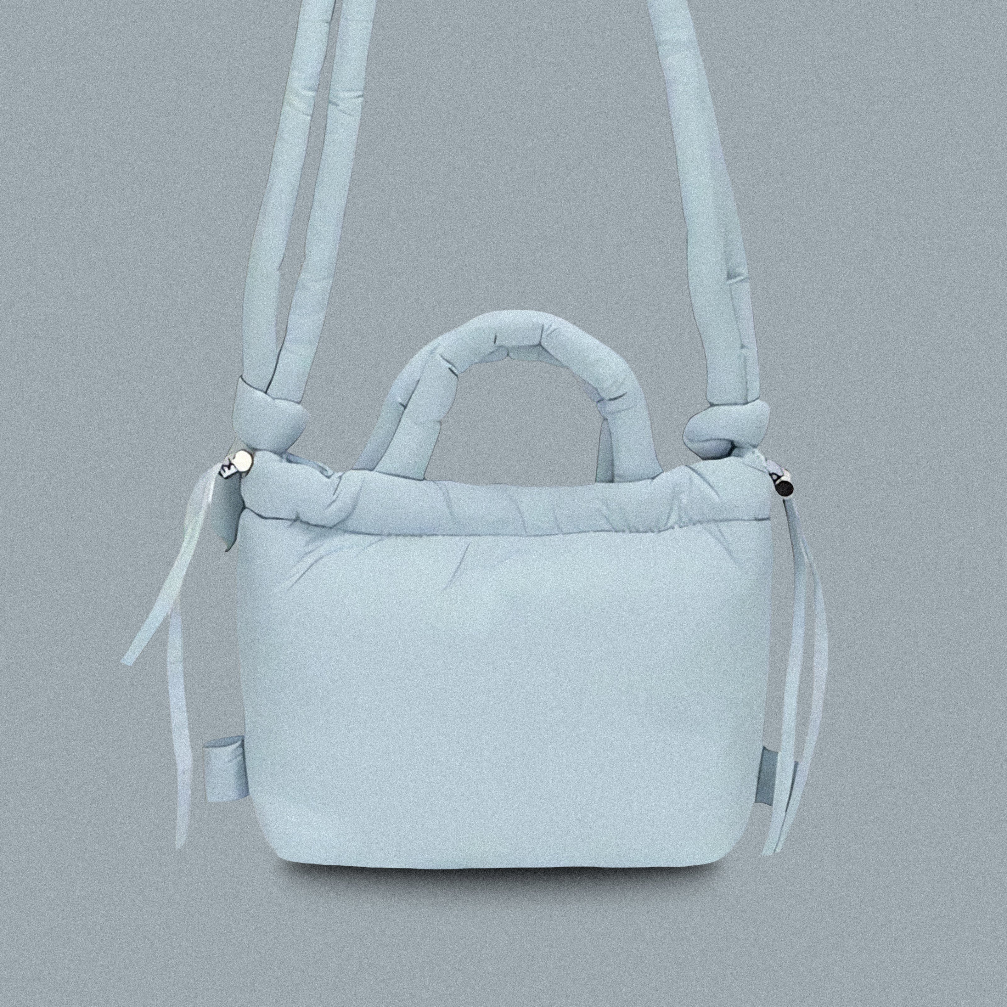 PLSH baby blue women’s designer puffer handbag on a blue background