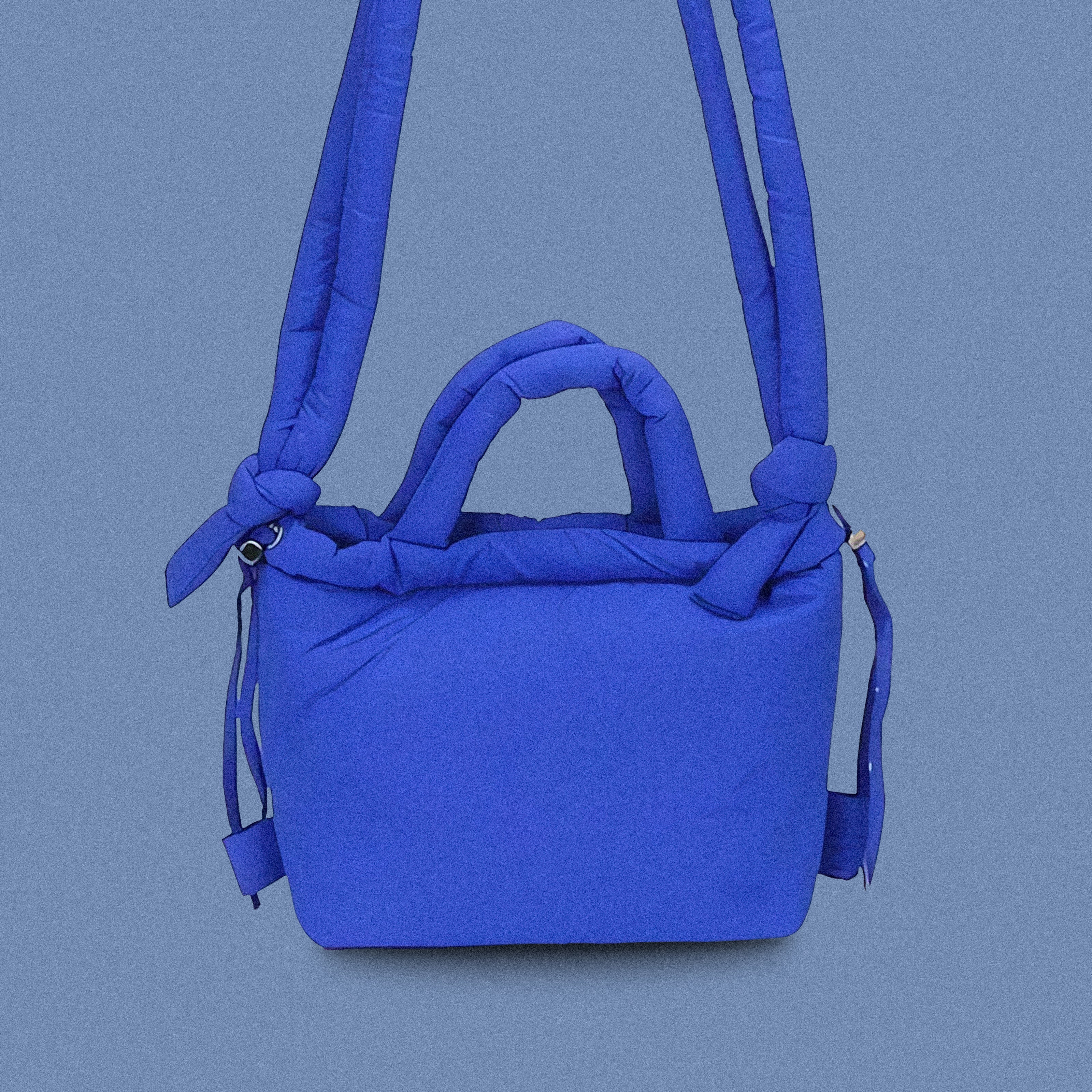 PLSH blue women’s designer puffer handbag on a blue background