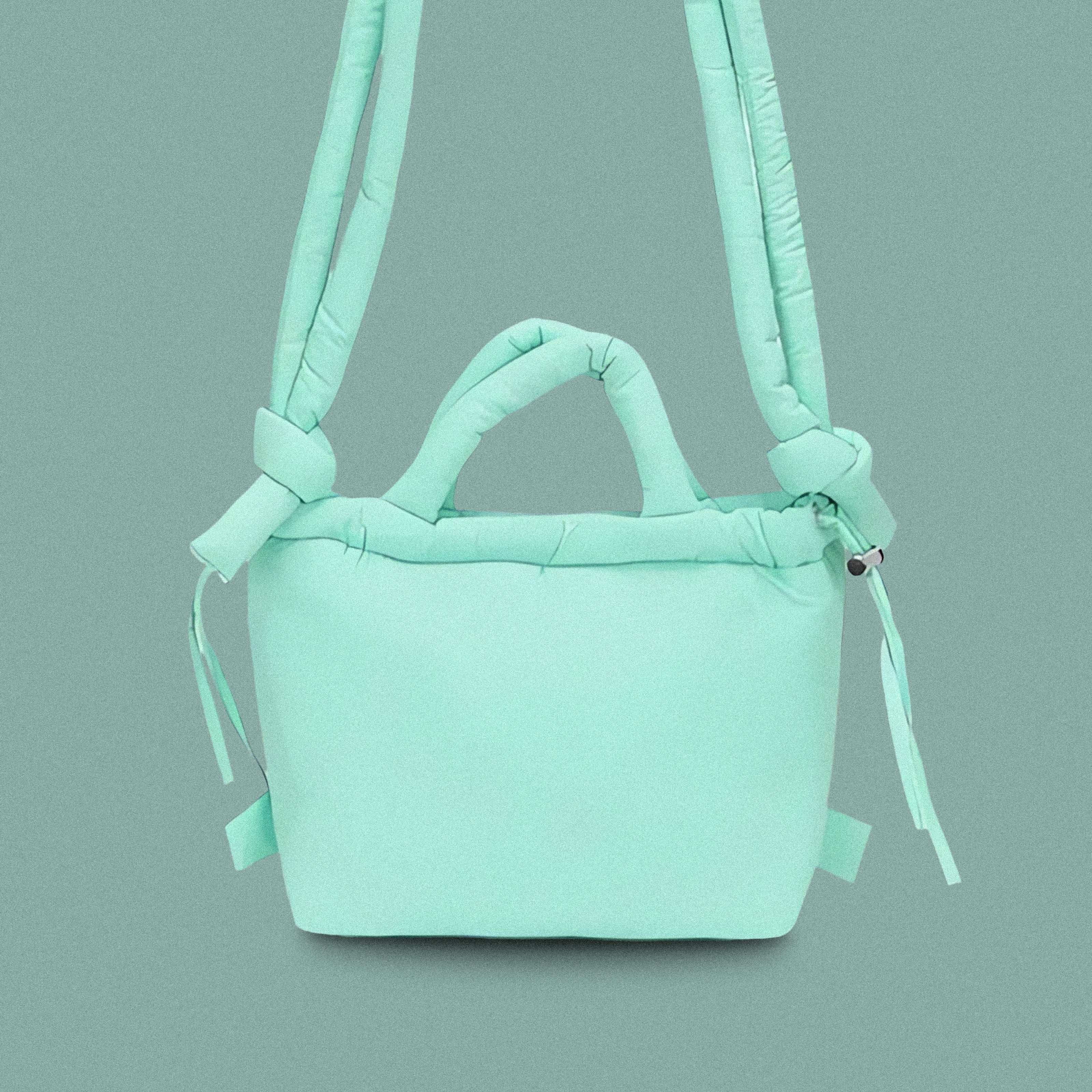 PLSH teal women’s designer puffer handbag on a teal background