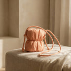 PLSH orange women's designer handbag with a strap on a beige surface