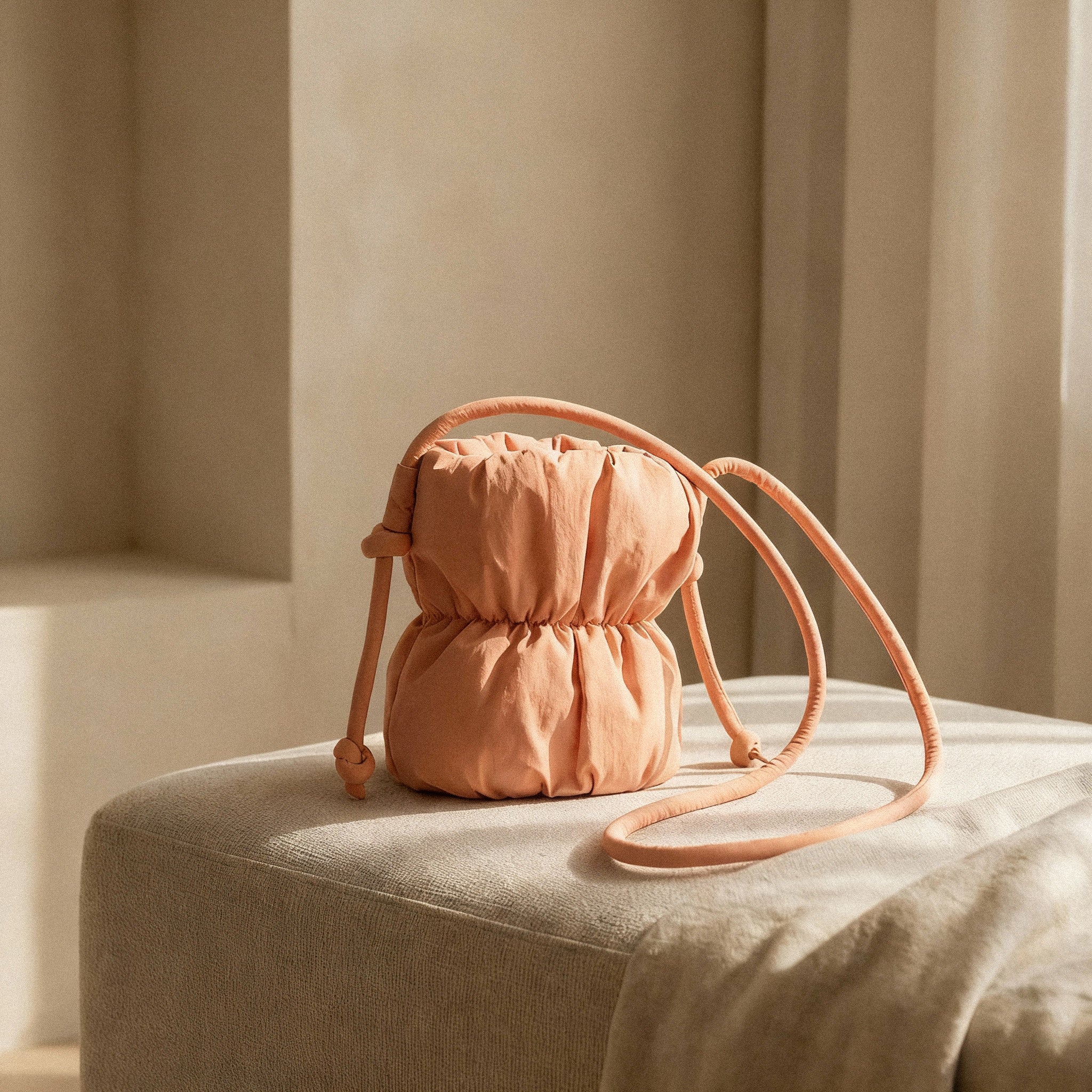 PLSH orange women's designer handbag with a strap on a beige surface