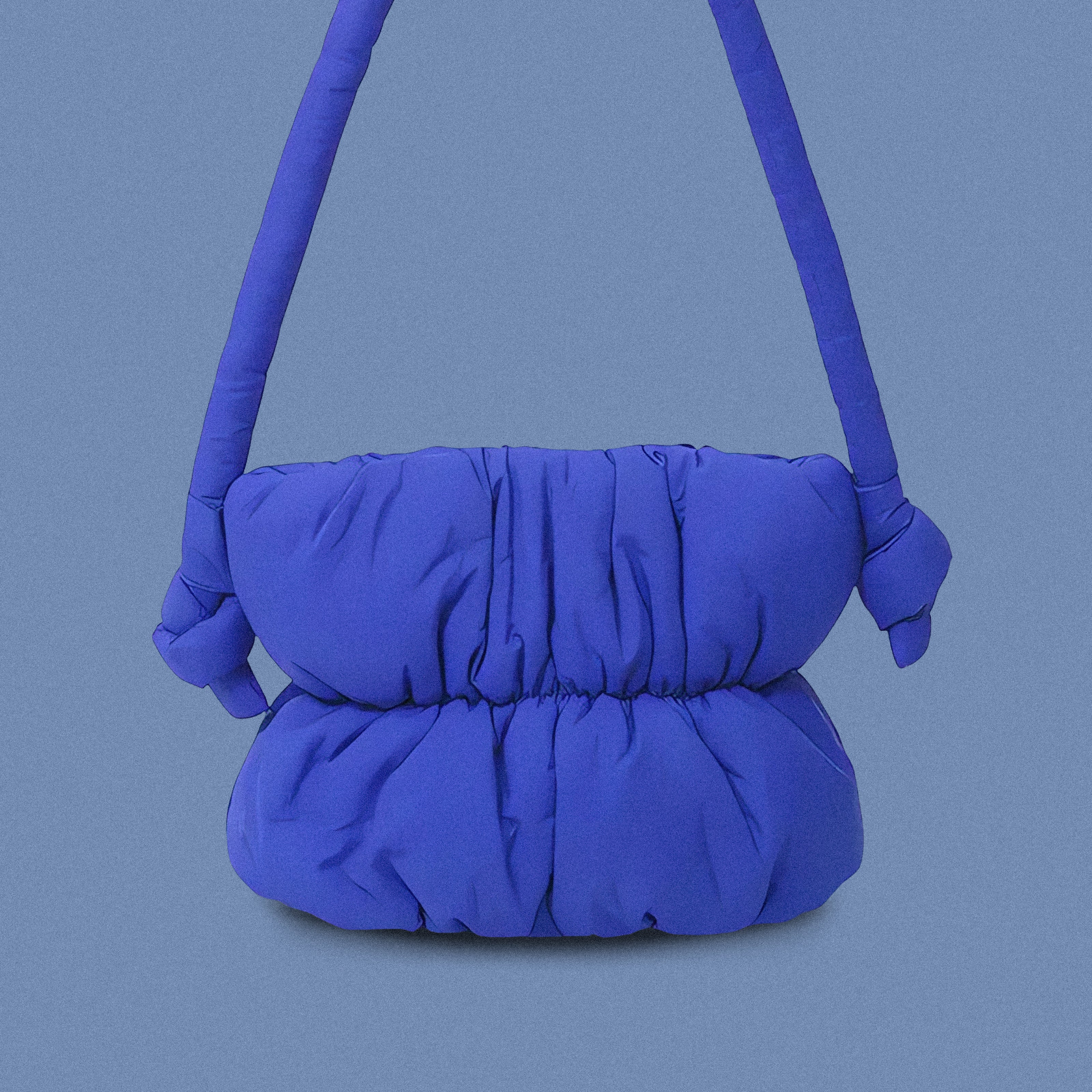 PLSH blue women’s designer puffer handbag on a blue background