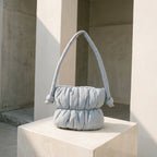 PLSH baby blue women's designer handbag on a stone pedestal with a neutral background