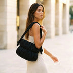 Woman carrying a PLSH women's designer black handbag in an urban setting