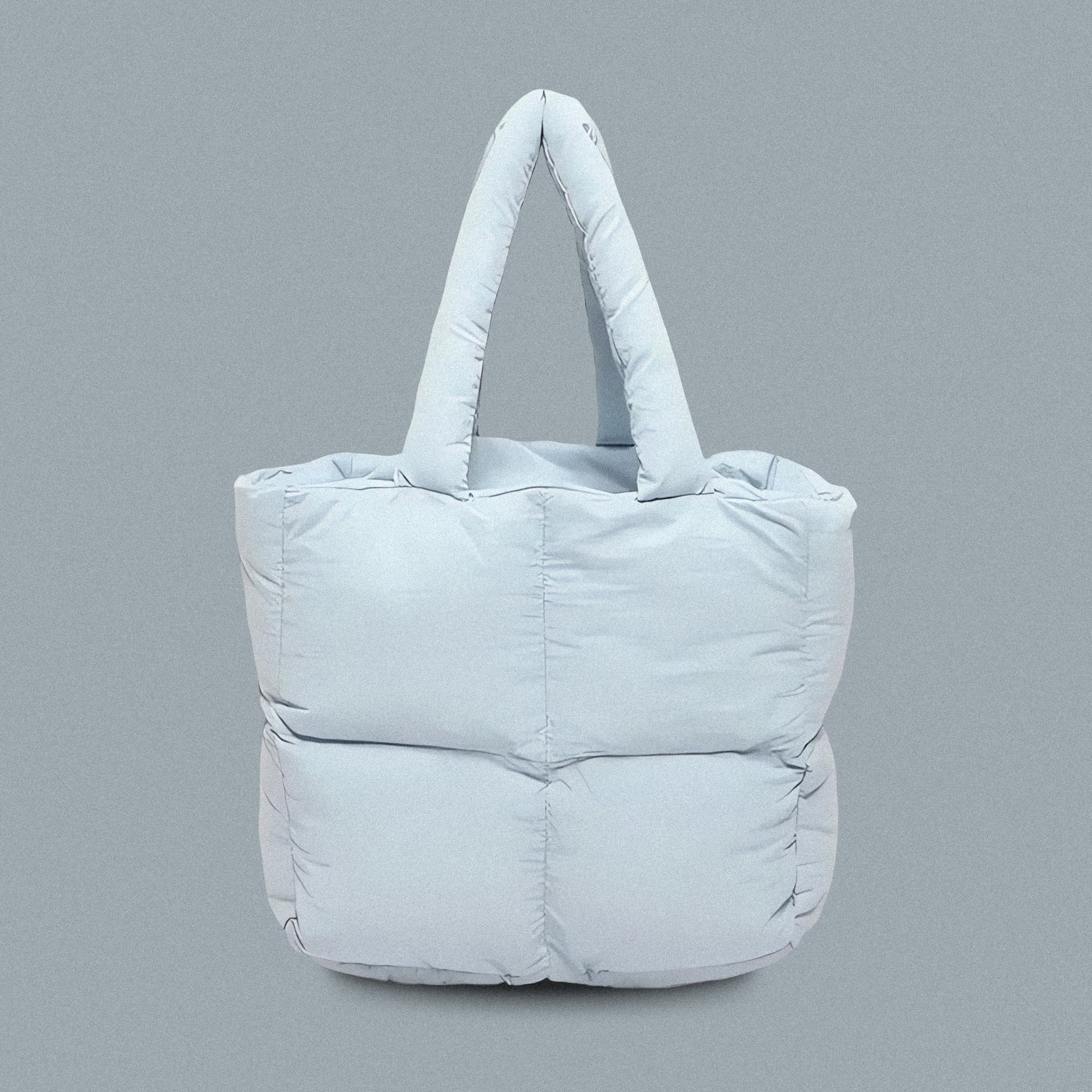 PLSH baby blue women’s designer puffer handbag on a blue background