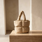 PLSH beige women's designer quilted handbag on a wooden surface with a neutral background