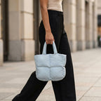 Woman holding a PLSH light blue designer quilted handbag on a city street