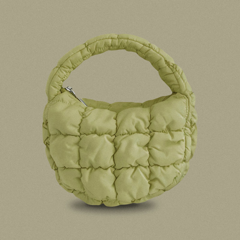 PLSH forest green women’s designer puffer handbag on a green background