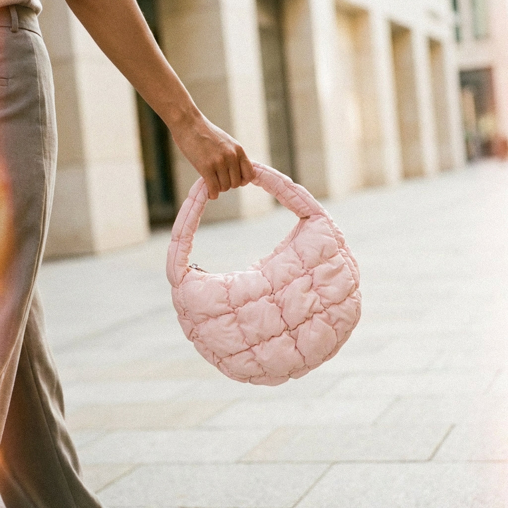 Woman holding a PLSH designer pink textured handbag on a city street