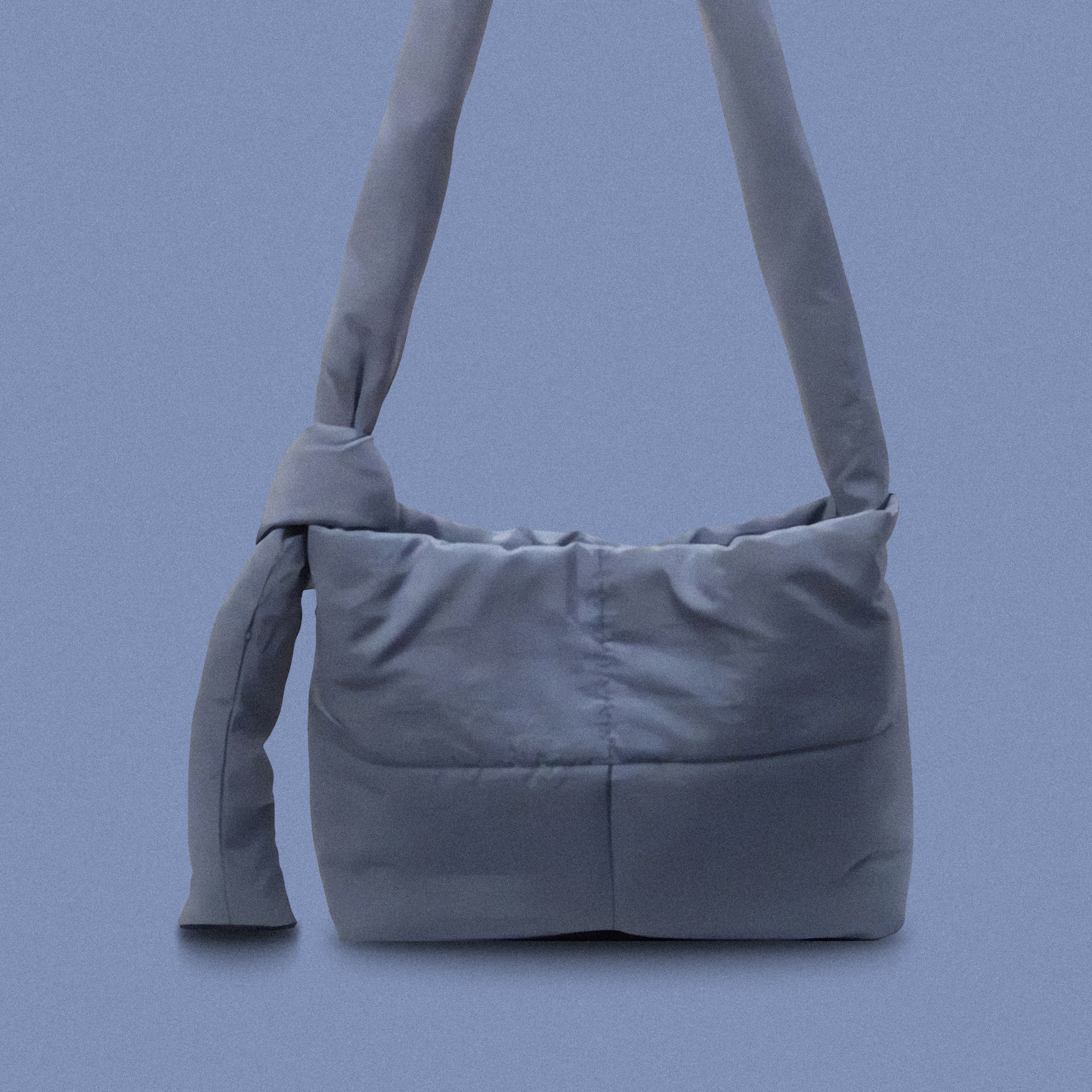 PLSH blue women’s designer puffer handbag on a blue background