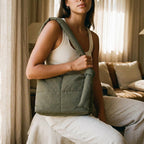 Woman holding a PLSH designer green handbag in a cozy living room