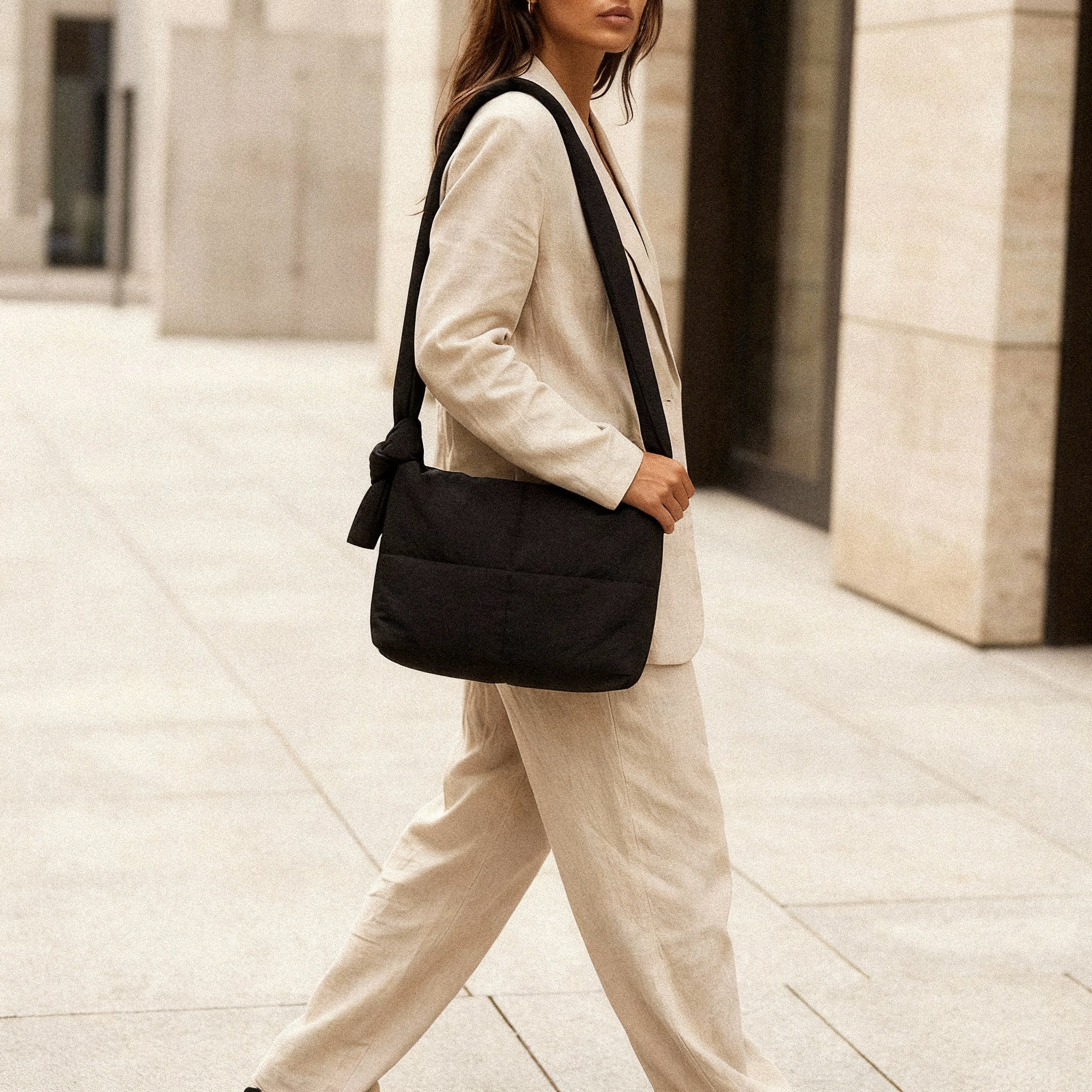 Woman wearing a PLSH designer black handbag in an urban setting