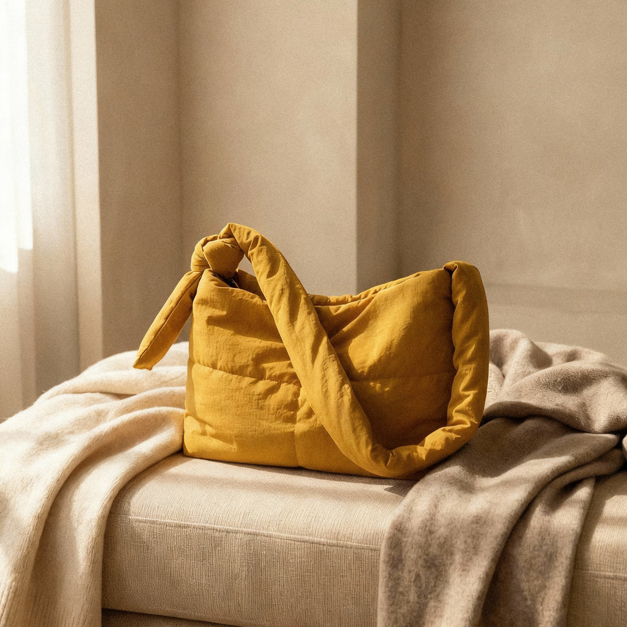 PLSH yellow women's designer quilted handbag on a beige sofa with soft lighting