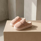 Pair of pink PLSH women's premium slippers on a beige surface with a neutral background